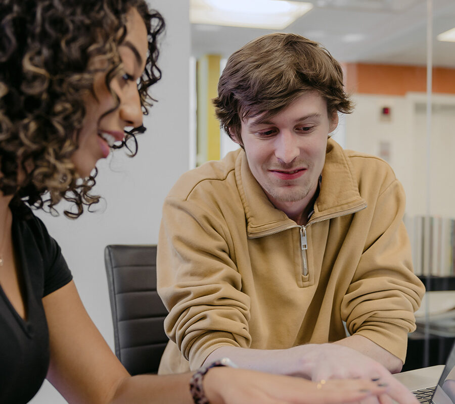 Two business administration students study together at a laptop