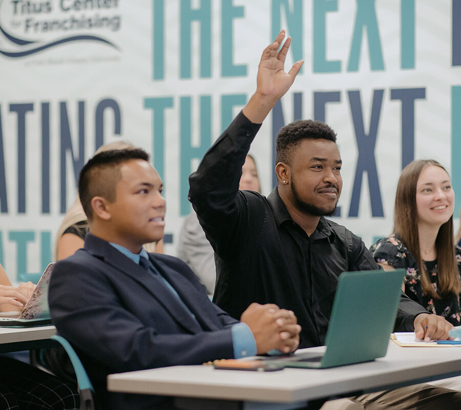 Student raises his hand in classroom lecture.