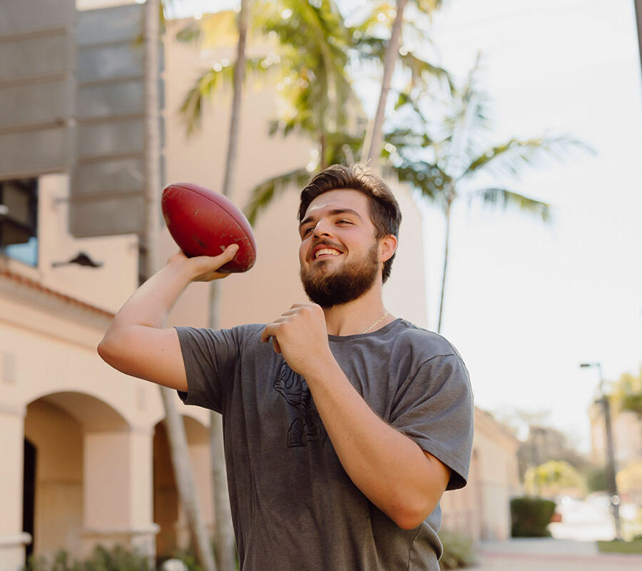 physical education student throws a football on campus.